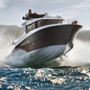 Dynamic powerboat slicing through ocean waves with mountains in the background, showcasing speed and adventure.