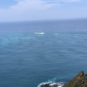 Ocean view from a coastal cliff with distant waves and blue sky, perfect for peaceful powerboating adventures.