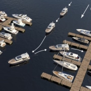 Powerboats maneuvering in a marina with docks, guided by wind direction and arrows, illustrating effective docking techniques.