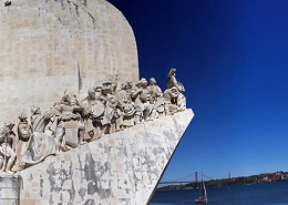 Stone monument with explorers overlooking a deep blue river, perfect backdrop for a Lisbon powerboating adventure.