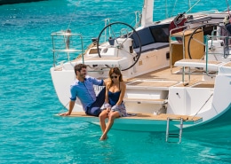 Couple enjoying a sunny day on a luxurious powerboat over clear turquoise waters.