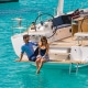 Couple enjoying a sunny day on a luxurious powerboat over clear turquoise waters.