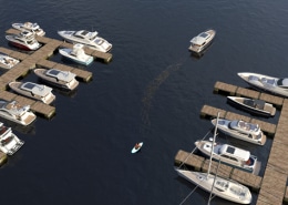 Aerial view of luxury powerboats docked at a marina, with a lone kayaker paddling between the piers.