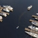 Aerial view of luxury powerboats docked at a marina, with a lone kayaker paddling between the piers.