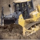 Bulldozer moving sand on a construction site, showcasing powerful machinery in action.