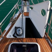 Close-up of a powerboat anchor locker with winch on teak deck, showcasing marine hardware and efficient boat design.