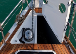 Close-up of a powerboat anchor locker with winch on teak deck, showcasing marine hardware and efficient boat design.