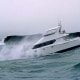 Powerboat navigating rough seas against rocky cliffs, showcasing thrilling marine adventure and wave-crashing action.