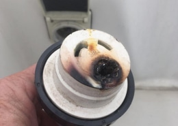 Close-up of a damaged 30A powerboat shore power plug, showing burnt contacts. Safety warning for marine electrical systems.