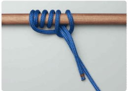 Blue rope tied with figure-eight knot on wooden rod, essential powerboating skill for secure docking and safety.