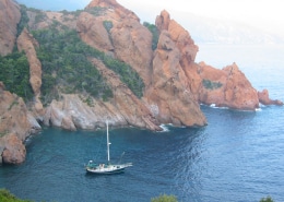 Sailboat navigating serene waters near stunning rocky cliffs, perfect for marine adventures and scenic exploration.