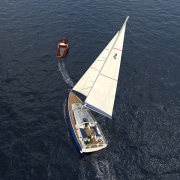 Aerial view of a powerboat towing a sailboat on the ocean.