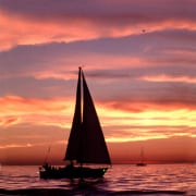 Silhouette of a sailboat at sunset, gliding over calm waters under a vibrant sky. Perfect evening for sailing adventures.