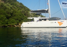 Powerboat anchored near lush green coast under clear skies, highlighting serene water adventure and NauticEd branding.