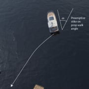 Top view of a powerboat maneuvering near docks with an illustrated prop walk angle guide, enhancing docking precision.