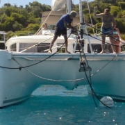 Catamaran crew anchoring in sunny waters, ensuring stable mooring. Perfect day for a powerboating adventure!