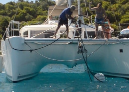 Catamaran crew anchoring in sunny waters, ensuring stable mooring. Perfect day for a powerboating adventure!