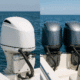 White and gray outboard boat engines on a boat in clear blue ocean water.