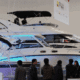 Luxury powerboats displayed at a boat show, drawing attention from visitors. Sleek design and modern features showcased.
