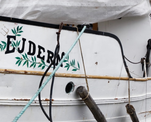 Close-up of a vintage boat exterior with EJDERN text and decorative leaves, showcasing nautical charm.