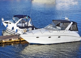 Two sleek powerboats moored at a dock, reflecting on calm blue waters under a clear sky. Ideal for leisure boating adventures.