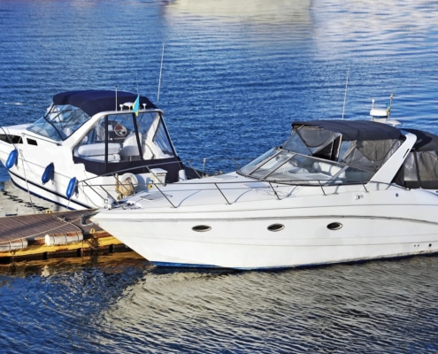 Two sleek powerboats moored at a dock, reflecting on calm blue waters under a clear sky. Ideal for leisure boating adventures.