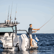 Man fishing on powerboat at sea, enjoying a sunny day with multiple rods mounted.