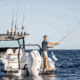 Man fishing on powerboat at sea, enjoying a sunny day with multiple rods mounted.