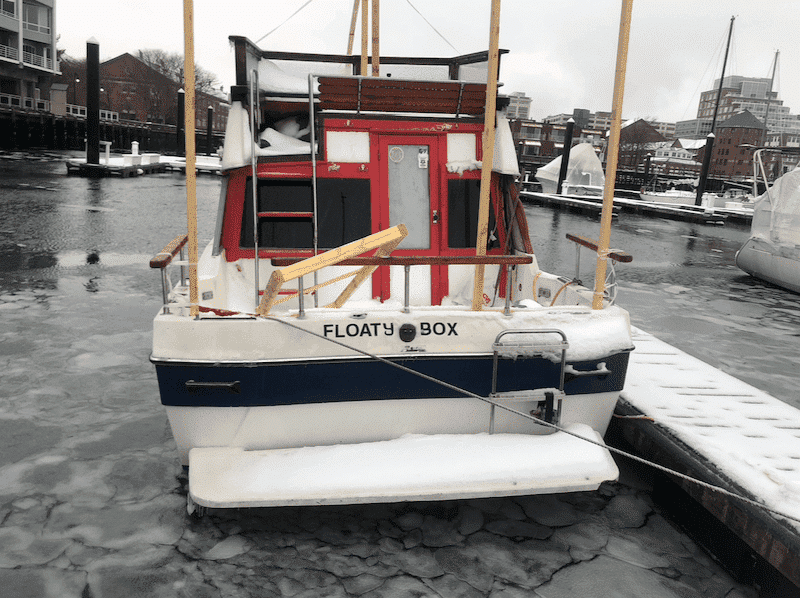 Small powerboat Floaty Box docked in icy marina, ready for adventure.