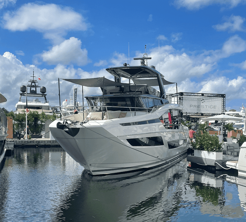 Luxury yacht docked at marina under blue sky, showcasing sleek design and opulent features.