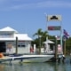 Powerboat fueling at a dockside marina, with gas prices displayed, offering essentials like bait and refreshments.